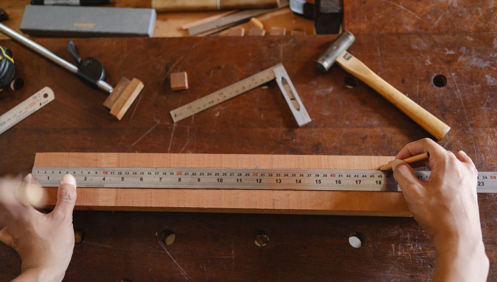 Un artisan mesure une pièce de bois dans son atelier