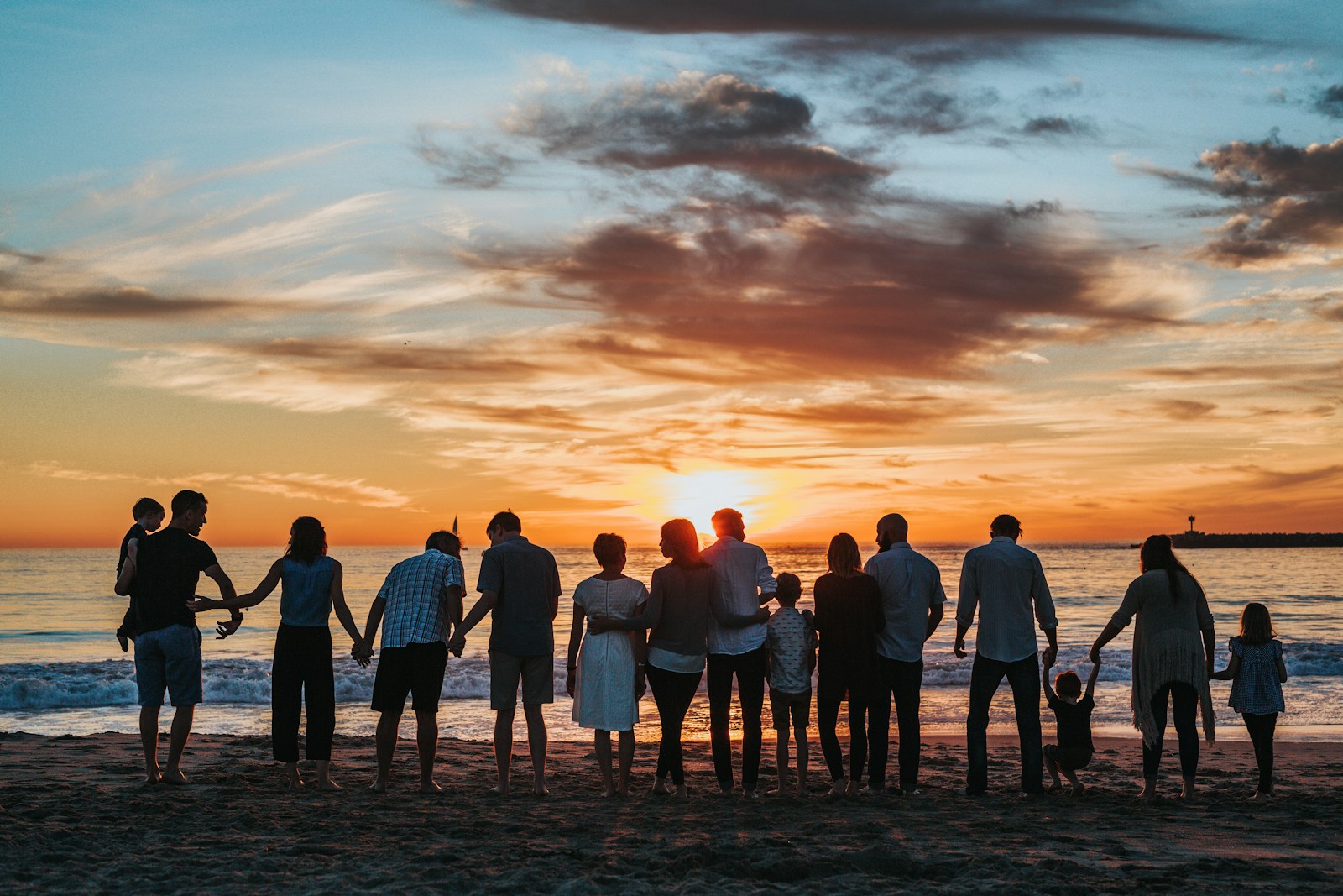 Famille réunie face à la mer au coucher du soleil.